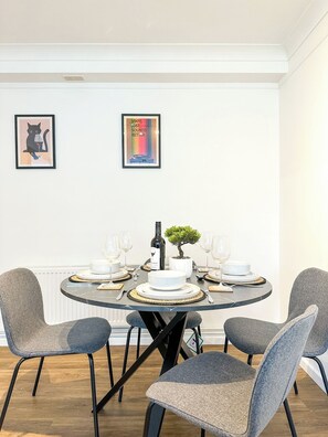 Comedor con una mesa redonda dispuesta para cuatro personas, rodeada de sillas tapizadas en gris.