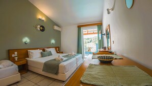 Habitación de hotel con cama, mesitas de noche, ventana con cortinas, espejo y vista a zonas verdes.