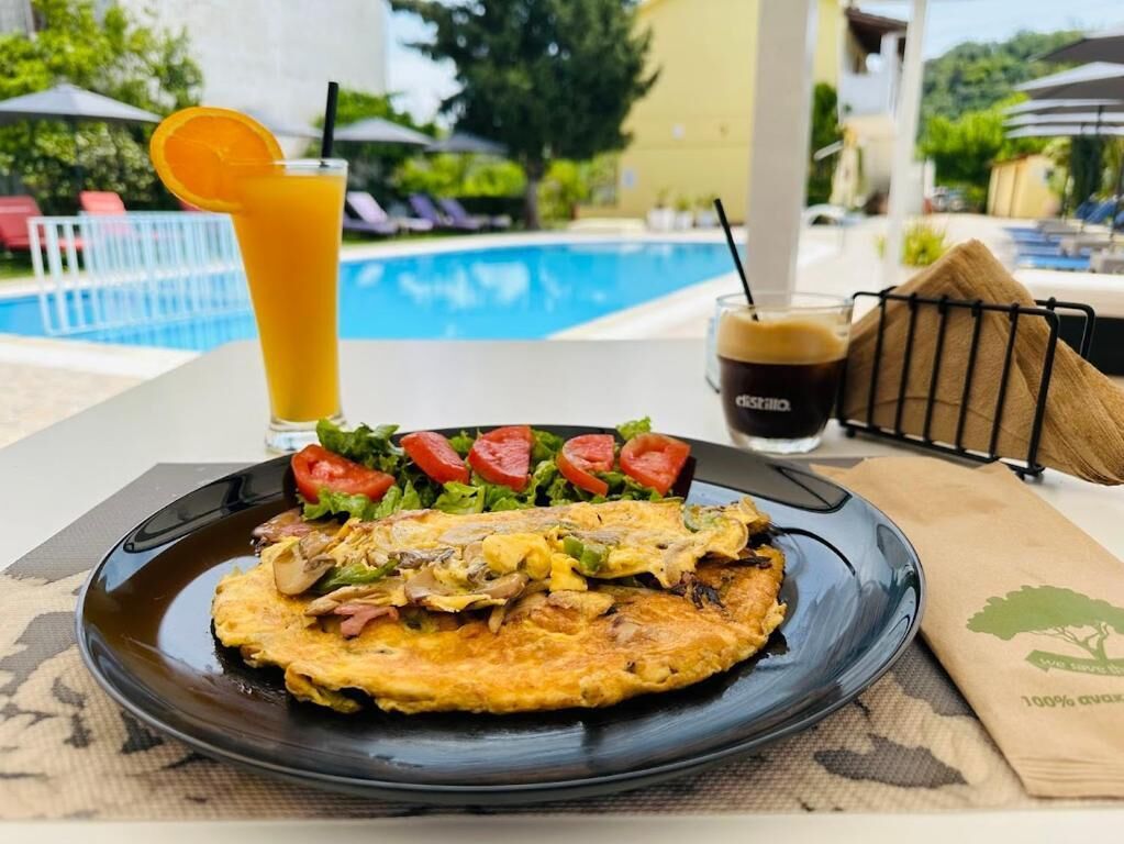 A breakfast plate with an omelette, salad, and a glass of orange juice.