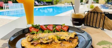 A breakfast plate with an omelette, salad, and a glass of orange juice.