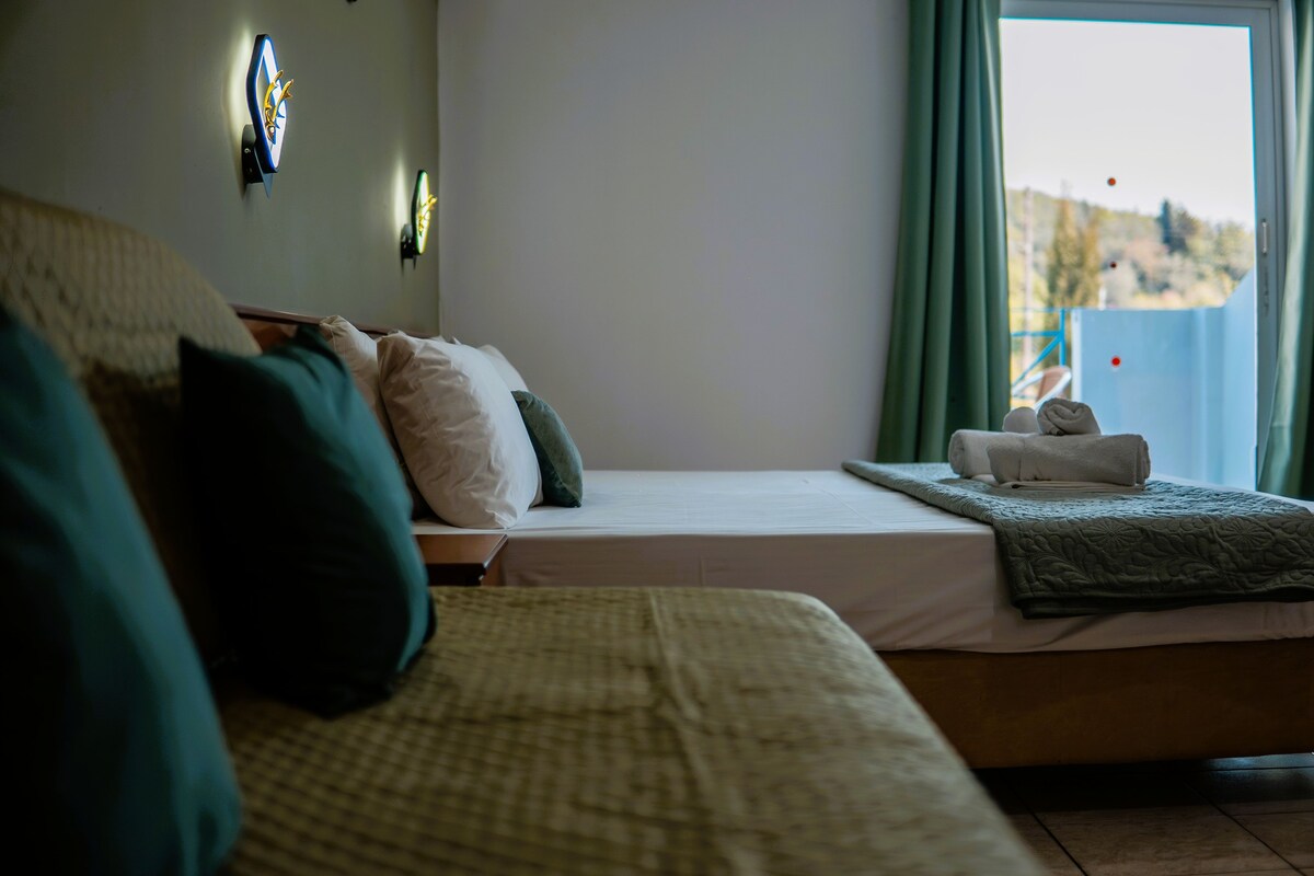 Ein Hotelzimmer mit Bett, Kissen, Decke, einer Wanduhr und einem Fenster mit Vorhängen.