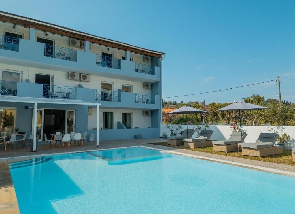 Un edificio de dos plantas con piscina, zona de estar exterior y patio cubierto.