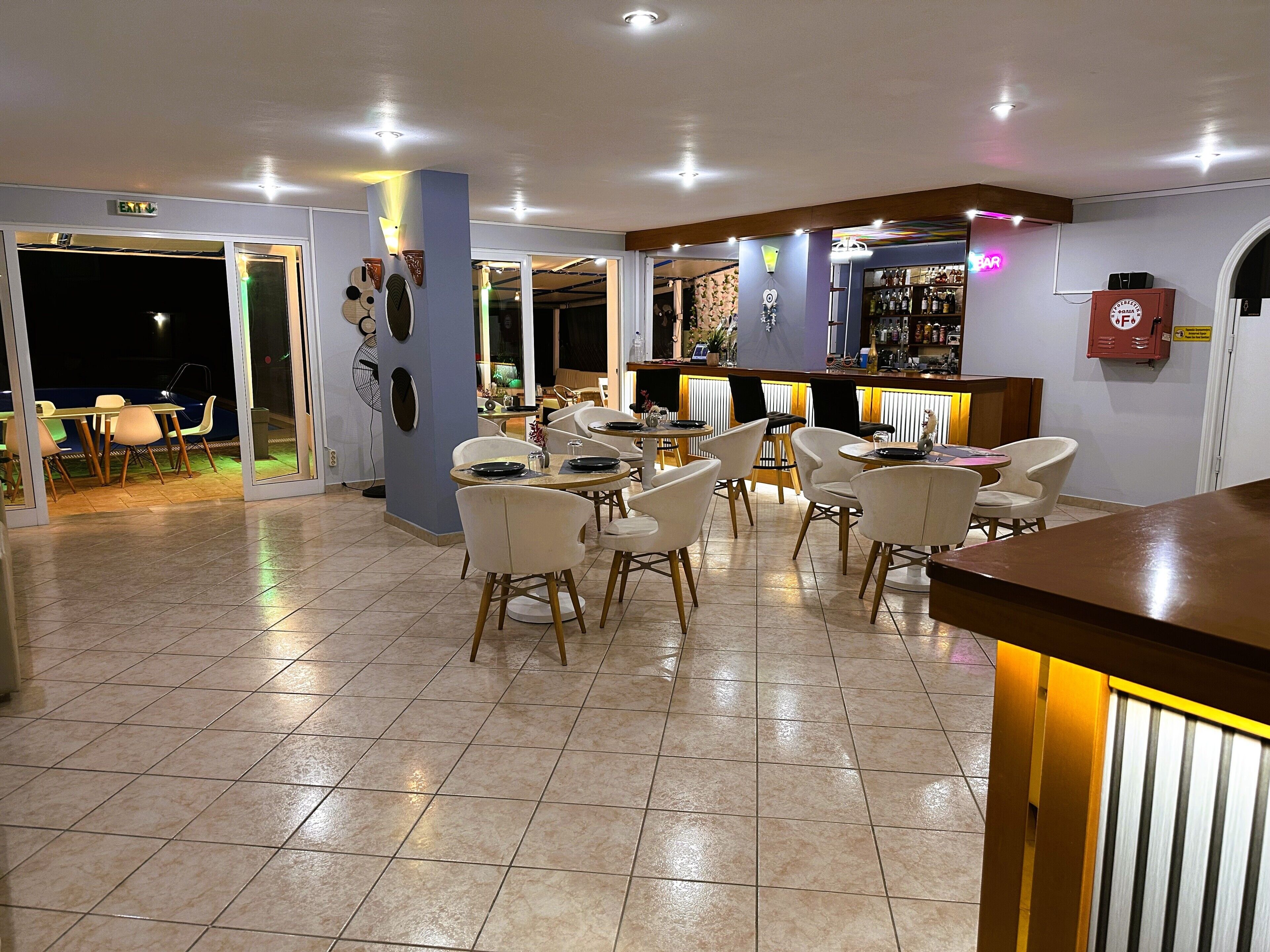 A hotel lobby with a bar area, dining tables, and chairs.