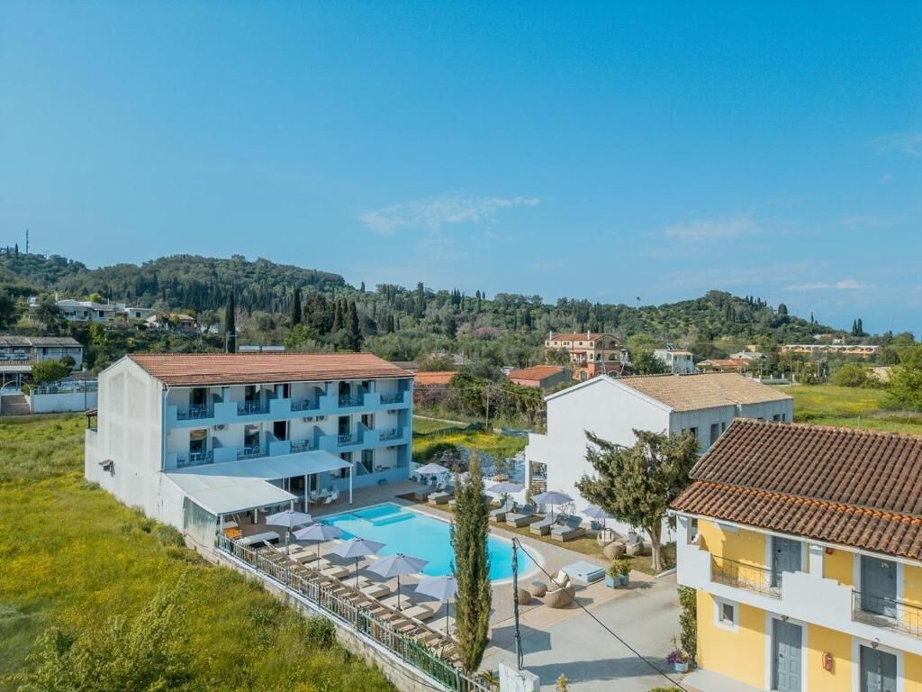 Un hotel con piscina, diversi piani e vista su un paesaggio collinare.