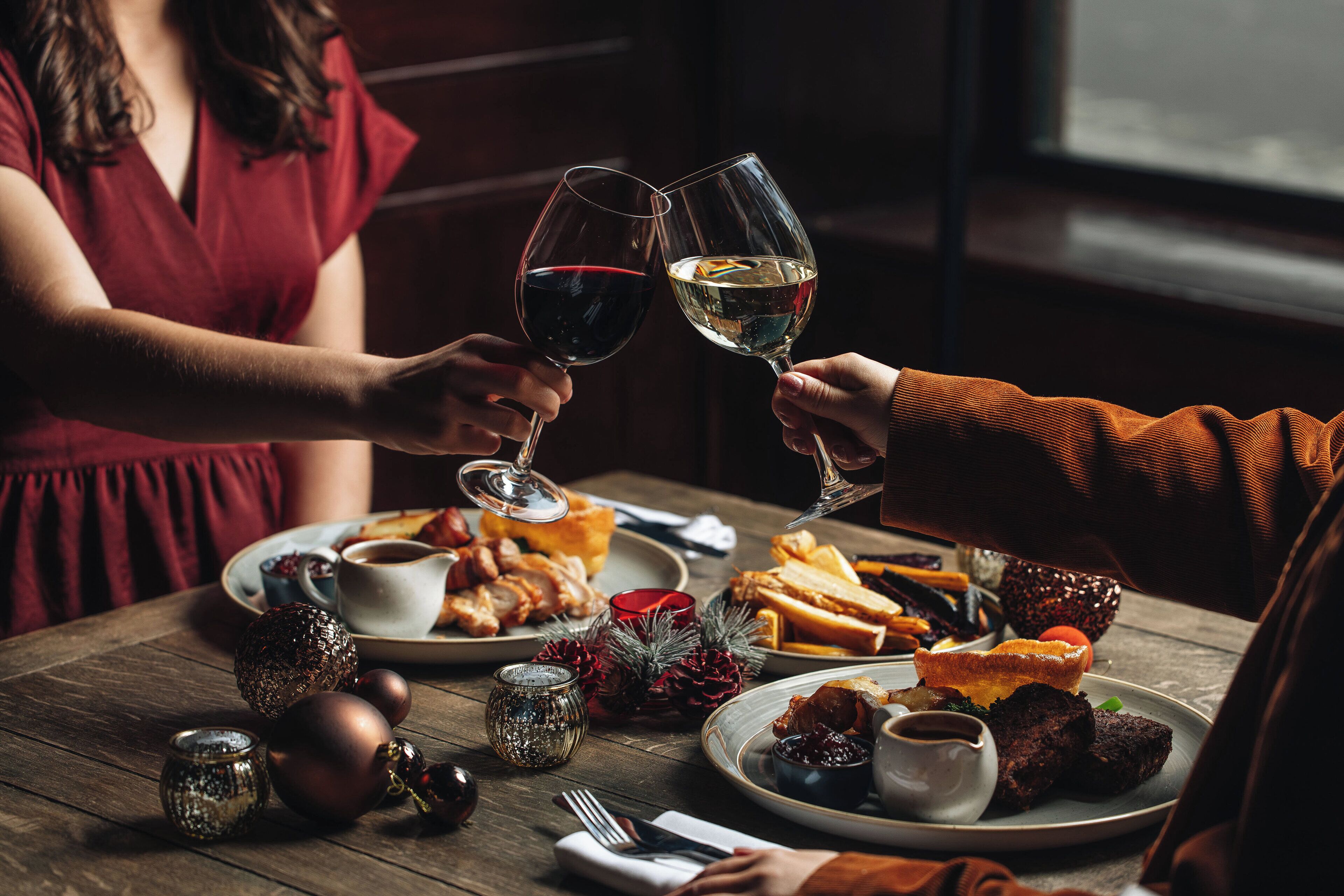 A dining table with plates of food, glasses of wine, and a candle.