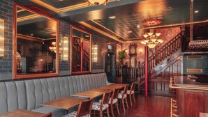 A restaurant with wooden tables and benches, a staircase, and a chandelier. - Hotel Indigo London Clerkenwell by IHG (London)