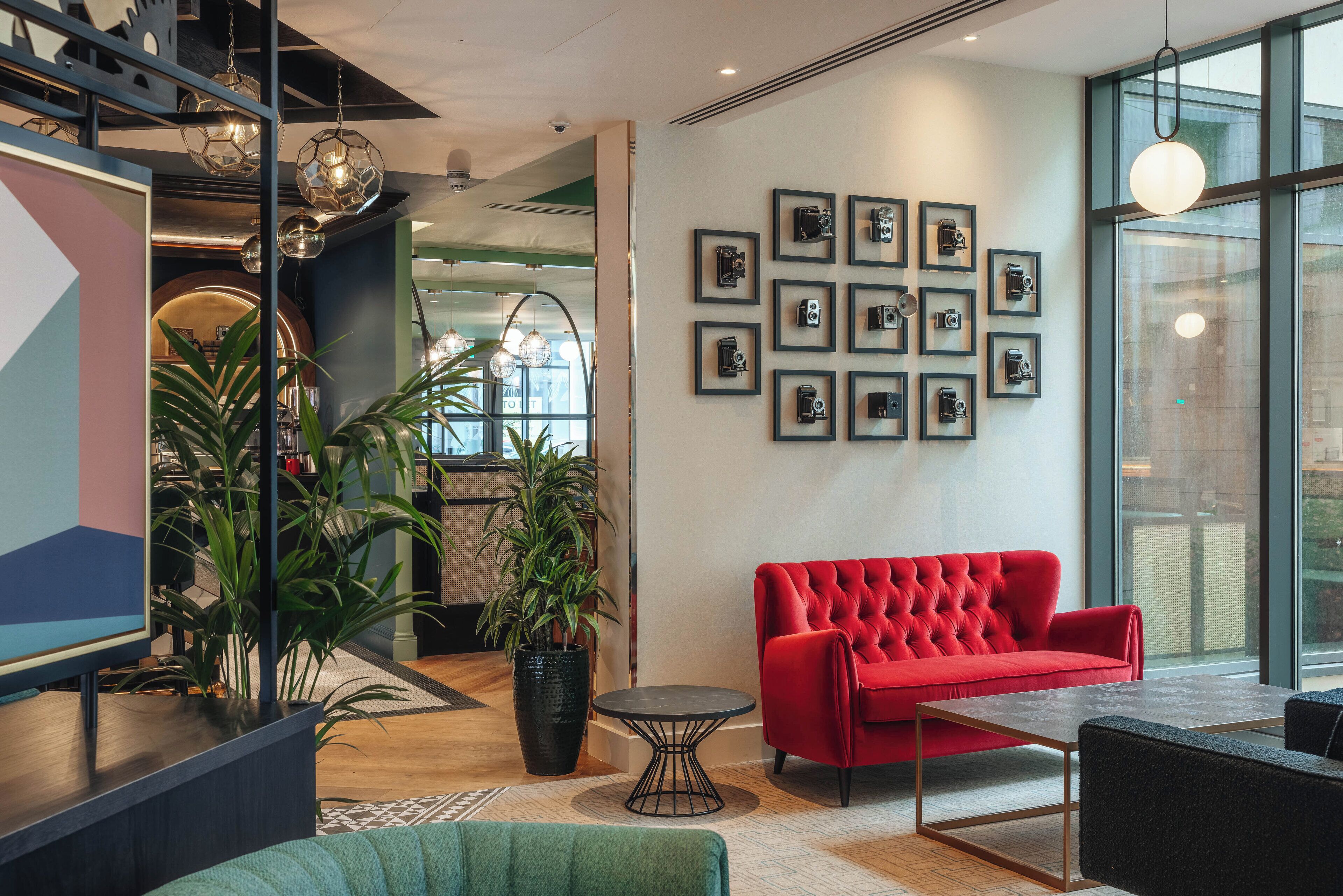 Un intérieur moderne avec un canapé rouge, une table ronde et un mur recouvert de photographies encadrées.