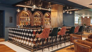 A bar area with a patterned tile backsplash, multiple bar stools, and a variety of bottles on shelves. - Hotel Indigo London Clerkenwell by IHG (London)