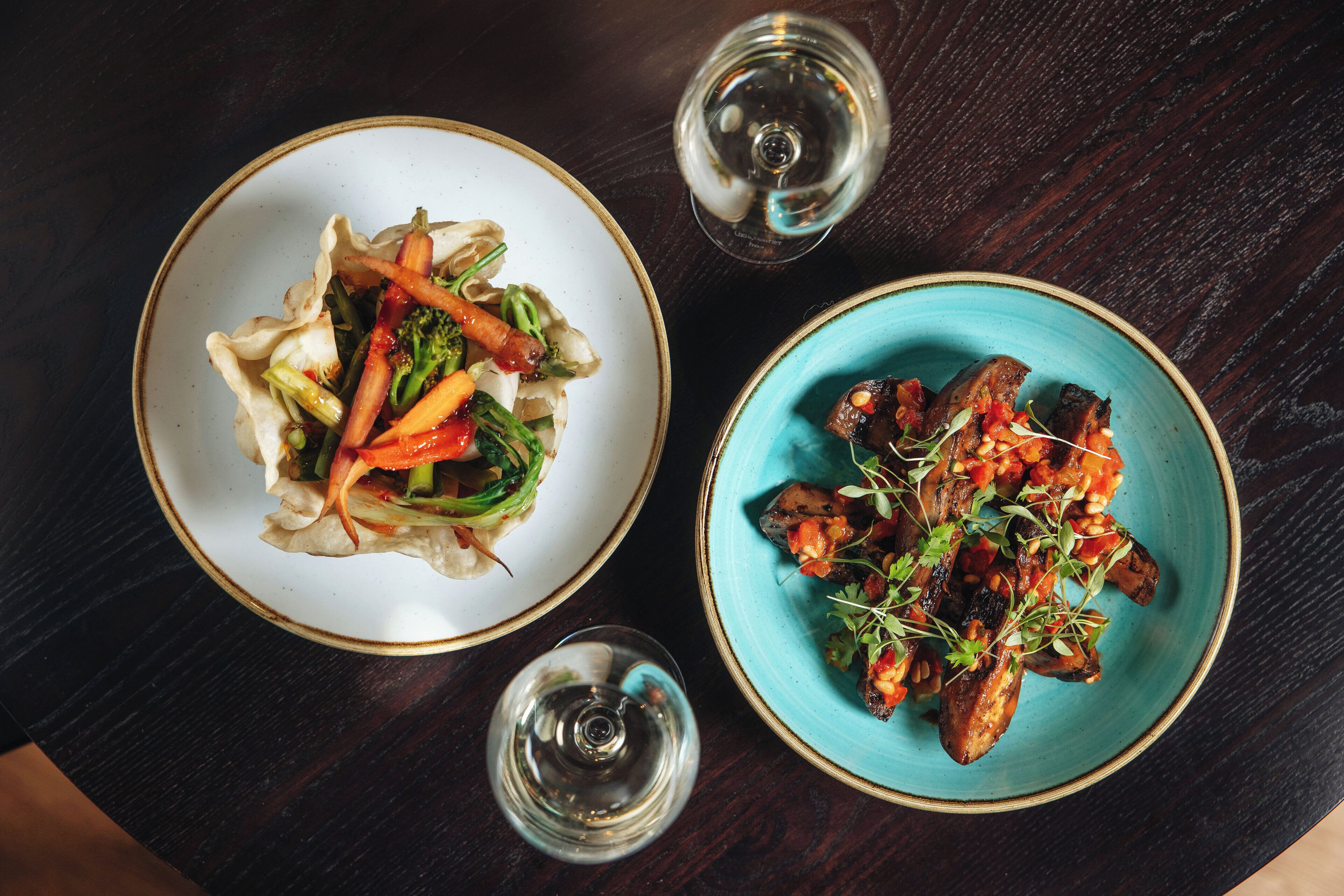 Two plates of food on a dark wooden table.