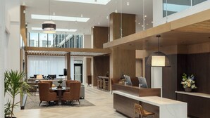 Un hall amplio con mostrador de recepción, zona de estar y escalera que conduce a pisos superiores.