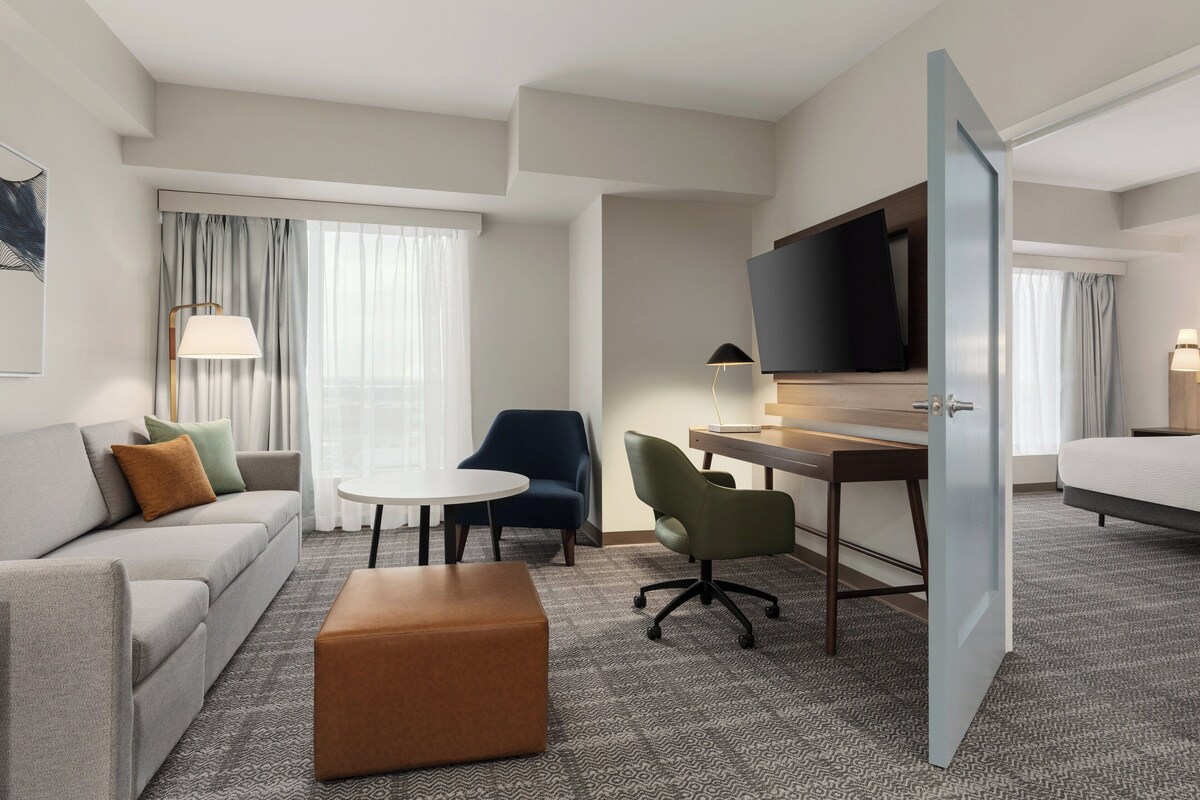 Una habitación de hotel con sofá, escritorio, televisor, silla y cama.