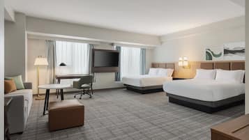 A hotel room with two beds, a desk, a chair, a TV, and a window with curtains.
