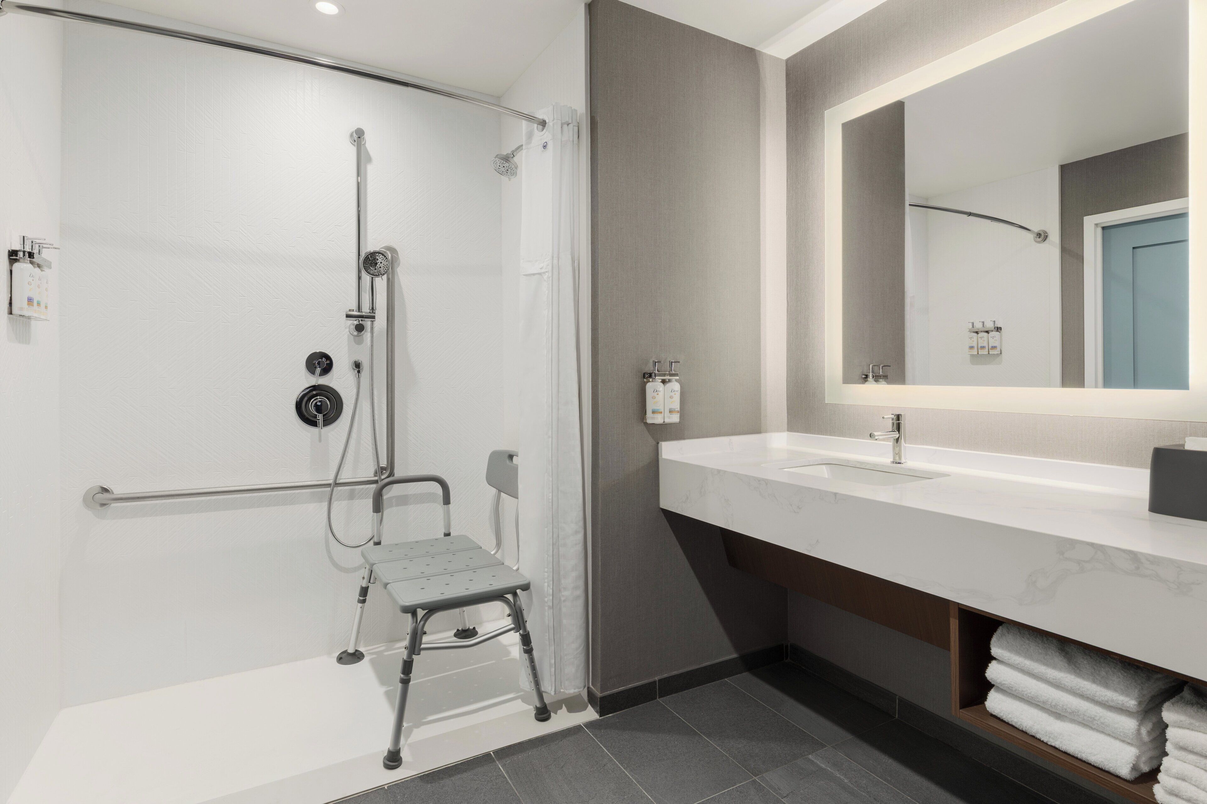 A modern bathroom with a shower, a sink, a mirror, and a towel rack.