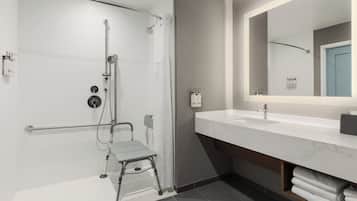 Ein modernes Badezimmer mit Dusche, Waschbecken, Spiegel und Handtuchhalter.