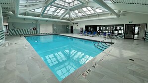 Piscina interior con señalización clara, techo de vidrio y zona poco profunda.