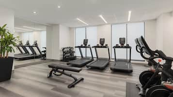 Un gimnasio con cintas de correr, una banca y equipo de pesas.