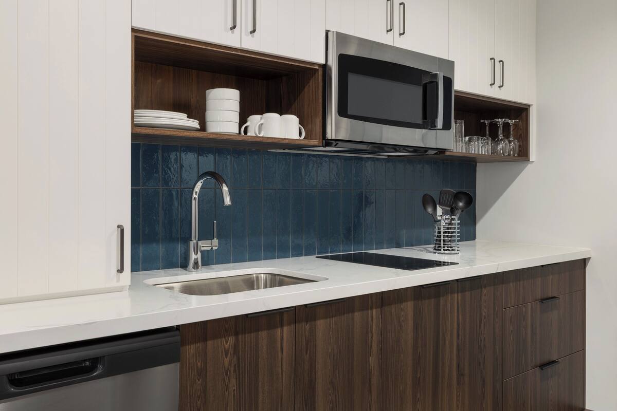 Una cocina moderna con microondas de acero inoxidable, pileta doble y armarios de madera.