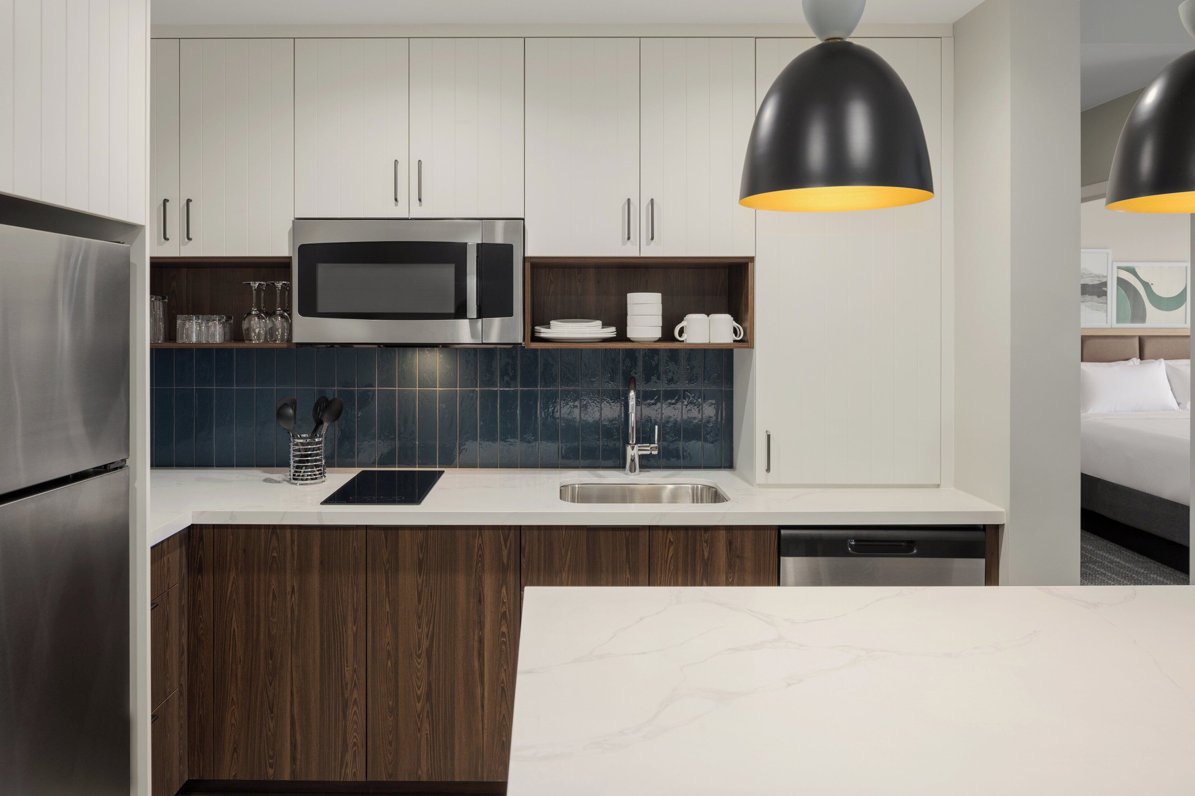 A modern kitchen with a microwave, sink, and wooden cabinets.