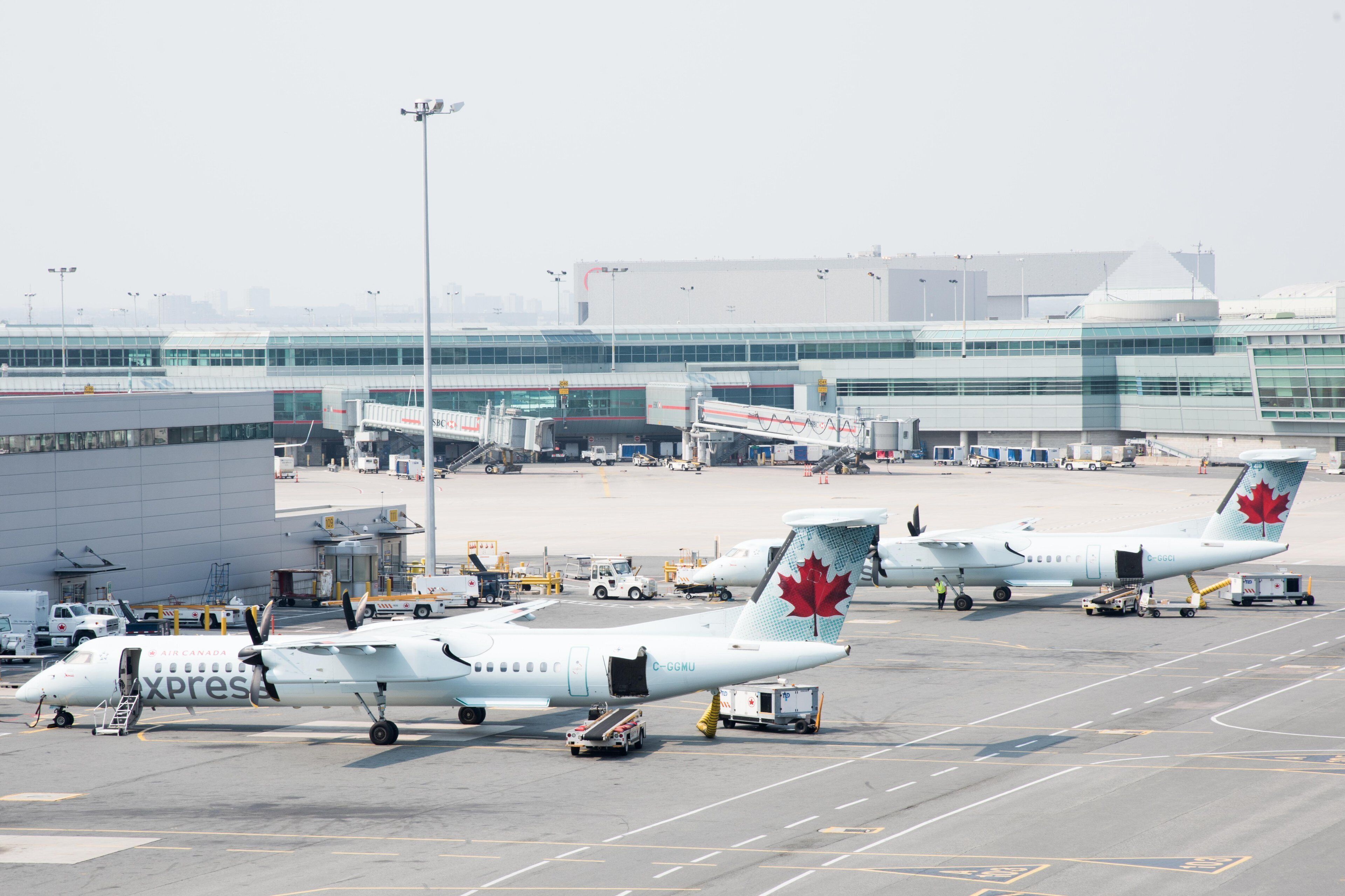 Suuri kaupallinen lentoasema, jossa useita Air Canada Express -yhtiön lentokoneita on pysäköitynä lähtöporteille, ja niihin on kytketty liukusillat.