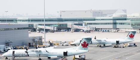Suuri kaupallinen lentoasema, jossa useita Air Canada Express -yhtiön lentokoneita on pysäköitynä lähtöporteille, ja niihin on kytketty liukusillat.