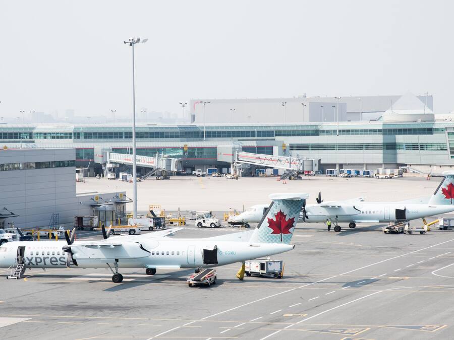 Un aeropuerto comercial con varios aviones Air Canada Express estacionados en puertas, conectados a puentes de acceso.