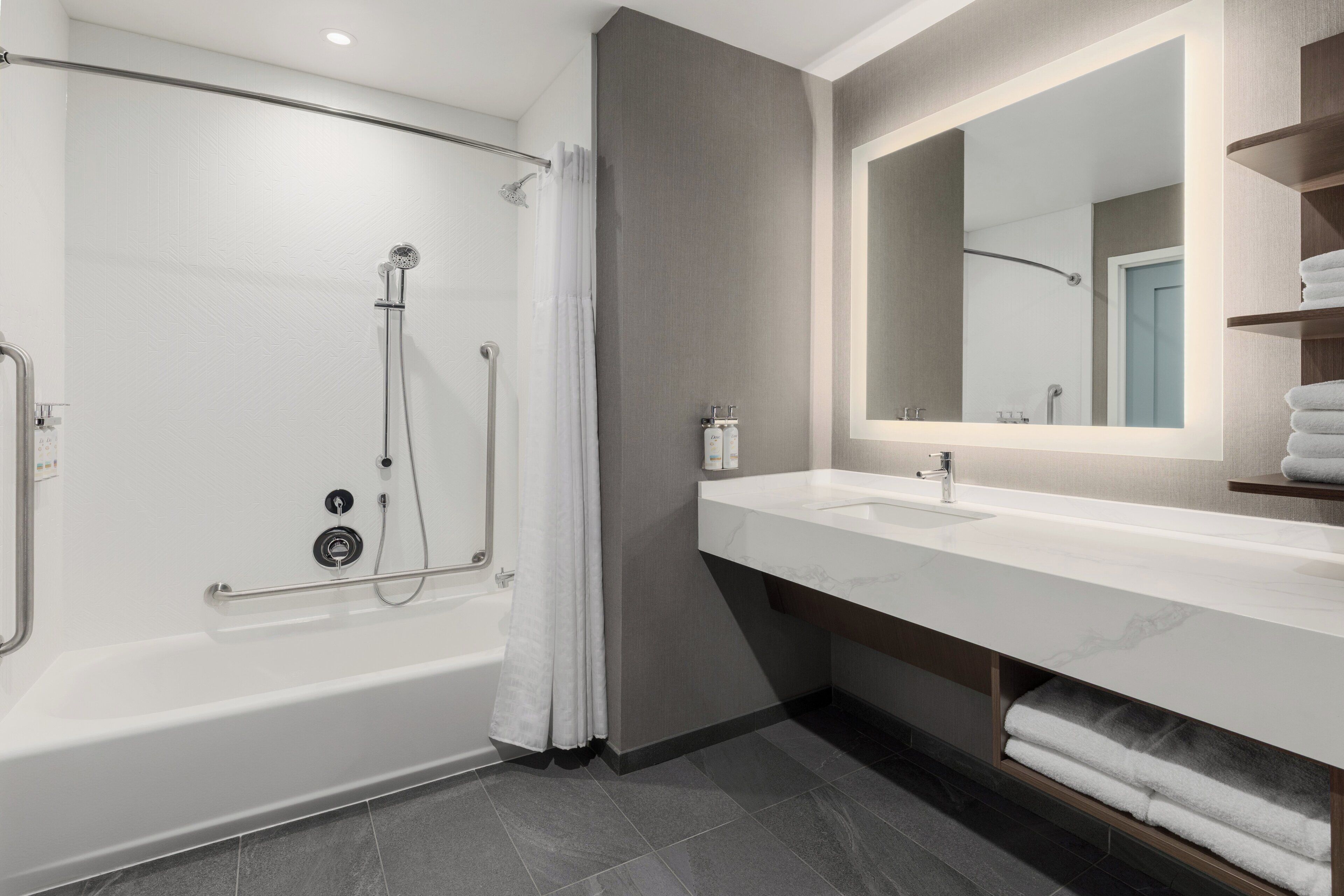 Un bagno moderno con vasca, doccia, lavabo con specchio e porta asciugamani.