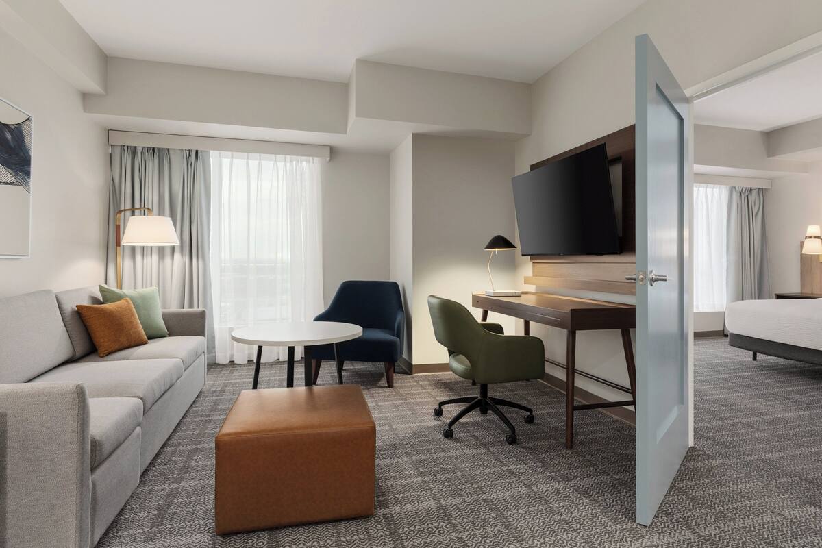 Una habitación de hotel con sofá, escritorio, televisor, silla y cama.