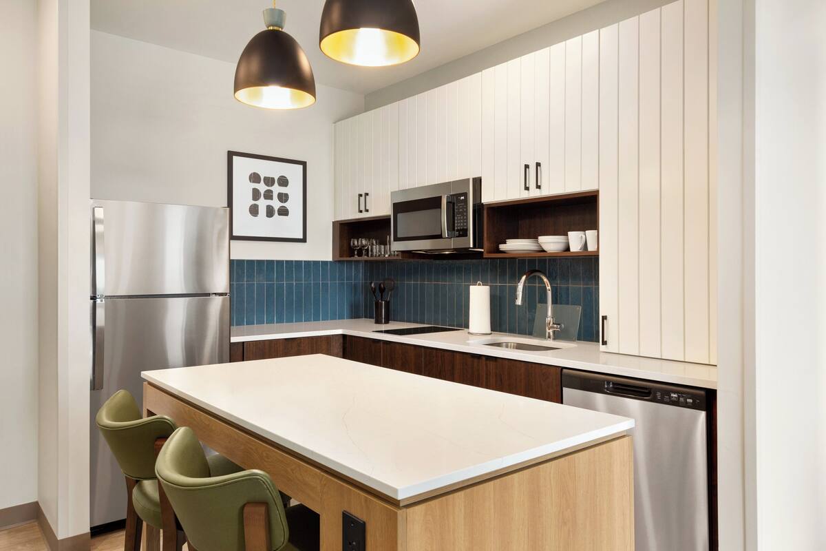 A modern kitchen with a central island, stainless steel appliances, and wooden cabinetry.