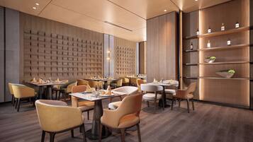 A modern restaurant with wooden panel walls, multiple dining tables, and chairs.
