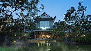 A traditional-style building with a sign for a holiday inn, surrounded by trees and a calm water body. - Holiday Inn Xuzhou Yunquan by IHG (Xuzhou)