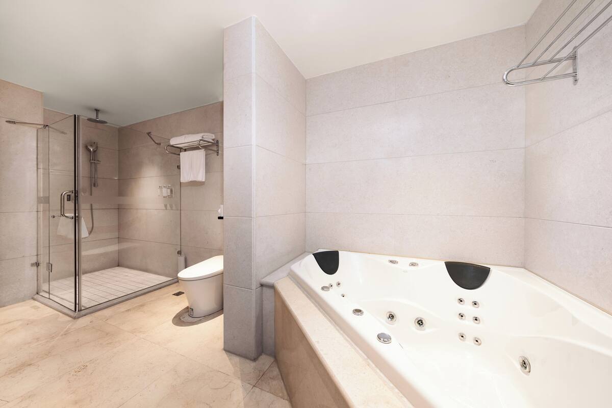 Ein modernes Badezimmer mit einer gläsernen Duschkabine, einer großzügigen Badewanne und einer Toilette.