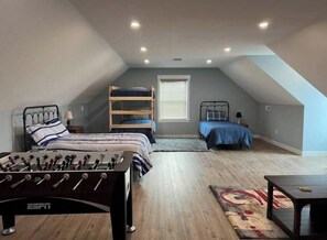 Cozy attic retreat with a single bed, bunk bed, and foosball table.