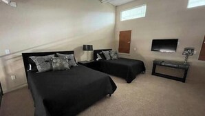 Habitació d'hotel amb dos llits, televisió, escriptori i finestra.