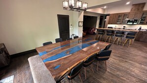 Una cocina moderna con armarios de madera, una isla grande con taburetes de bar y un comedor con una mesa larga y sillas.