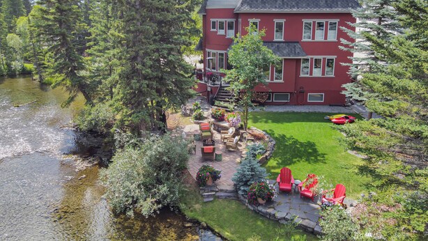 A red building with a stone patio and outdoor seating area. - The perfect place for family and friends to gather for a Rocky Mountain getaway! (Canmore)
