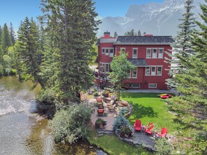 A red building with a stone patio and outdoor seating area. - The perfect place for family and friends to gather for a Rocky Mountain getaway! (Canmore)