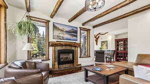 A cozy living room with leather sofas, a fireplace, and a large painting of a mountain landscape. - The perfect place for family and friends to gather for a Rocky Mountain getaway! (Canmore)
