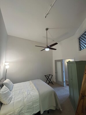 Cozy retreat with a single bed, nightstand, and ceiling fan.