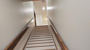 A staircase with wooden steps and white risers, leading upwards in a hallway with white walls and a wooden handrail on one side. - Charming 2-bedroom apartment in lovely Walnut Cove with AC, WiFi (Walnut Cove)