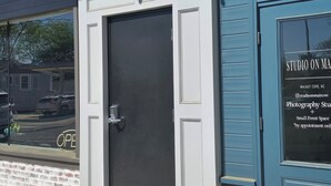 A building with a closed door, a window with a reflection of a parked car, and a sign indicating 'STUDIO ON MAIN' with a location in Walnut Cove, NC. - Charming 2-bedroom apartment in lovely Walnut Cove with AC, WiFi (Walnut Cove)