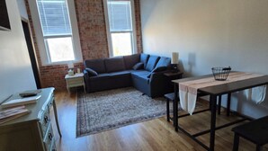 A living room with a sectional sofa, a dining table, and a ceiling fan. - Charming 2-bedroom apartment in lovely Walnut Cove with AC, WiFi (Walnut Cove)
