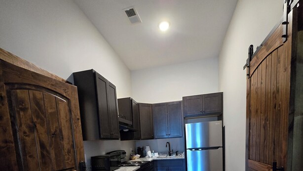 A compact kitchen with dark wooden cabinets, a stainless steel refrigerator, and a microwave. - Charming 2-bedroom apartment in lovely Walnut Cove with AC, WiFi (Walnut Cove)