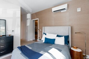 Ein modernes Schlafzimmer mit Bett, Nachttisch und Klimaanlage.