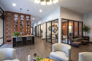 Una hall moderna con reception, area relax e pareti divisorie in vetro.