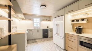 A modern kitchen with white cabinets, a black refrigerator, a coffee maker, and a patterned floor. - Sandy Cove 04 Tucker Inn (Happy Adventure)