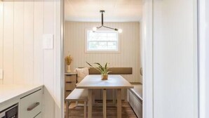 A kitchen with white cabinetry, a wooden dining table, and a window with natural light. - Sandy Cove 04 Tucker Inn (Happy Adventure)