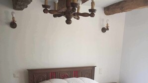 Un dormitorio con una cama de madera, cabecera de madera, una araña y una mesita de noche.