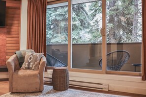 Et hyggeligt værelse med en læderlænestol, en fletstol og udsigt til en balkon med en stol.