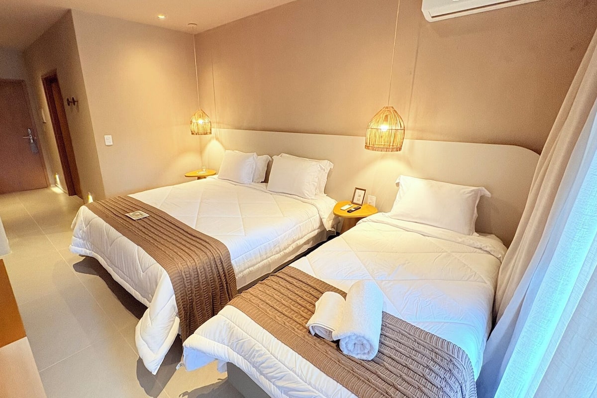 Ein Hotelzimmer mit zwei Betten, einem Nachttisch mit Lampe und einem kleinen Tisch mit Telefon und Buch.