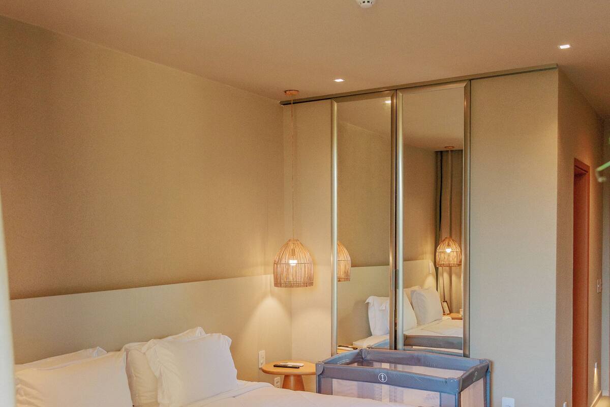 Ein Schlafzimmer mit einem großen Bett, einem Nachttisch, einem Spiegel und einer Wandleuchte.